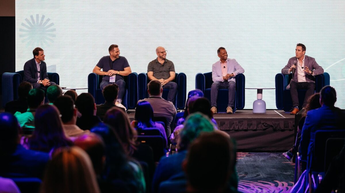 Photo of a panel on stage at Automate Sydney 2024, with Neil Rodgers holding the mic